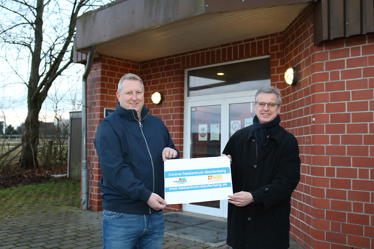 (v.li.) Nils Borcherding (Geschäftsführer, ASB-Kreisverband Göttingen-Land) und Bernd Grebenstein (Bürgermeister Gemeinde Staufenberg) mit dem Testzentrumsbanner, das auf das Angebot hinweist.